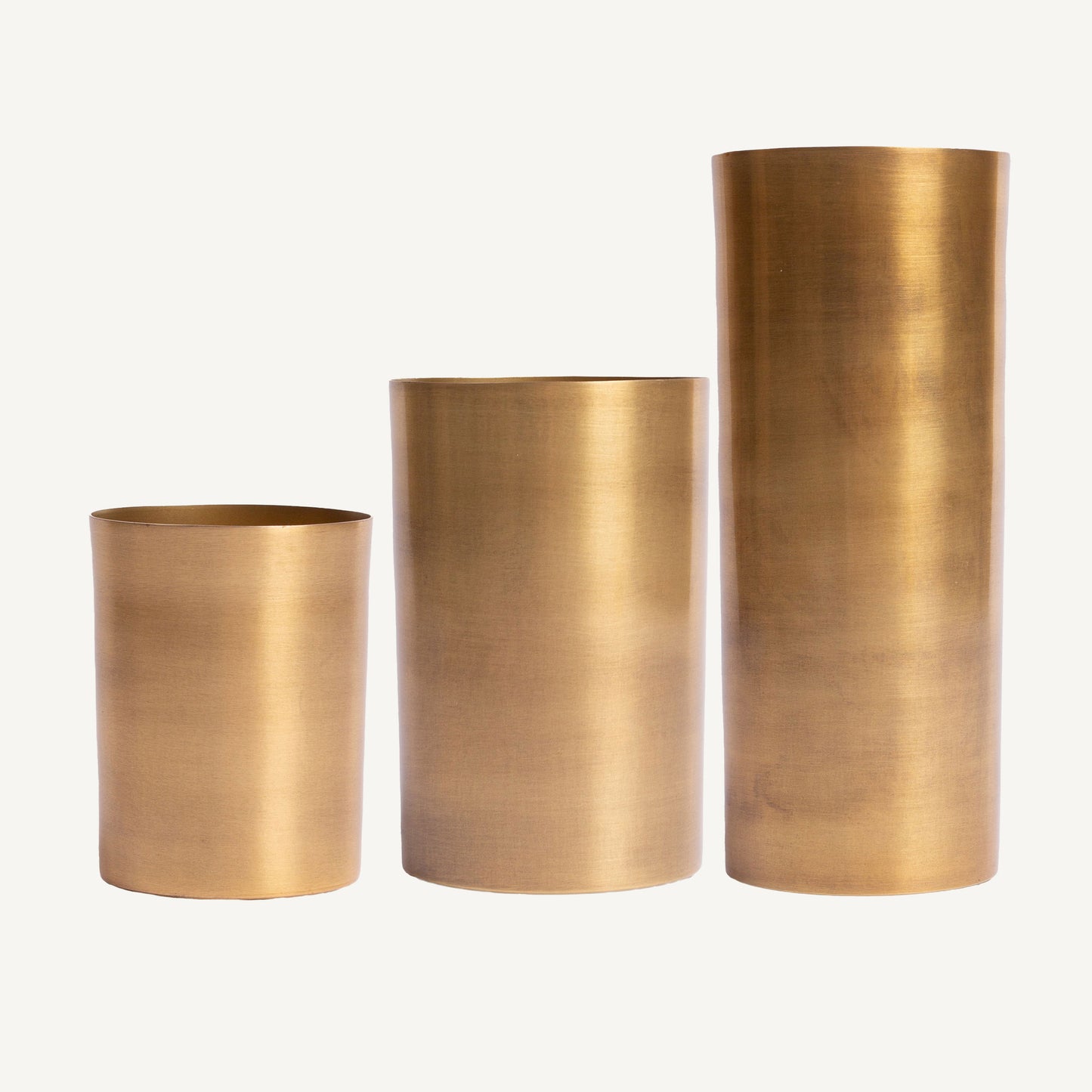 Three gold cylindrical vases of different sizes on a white background