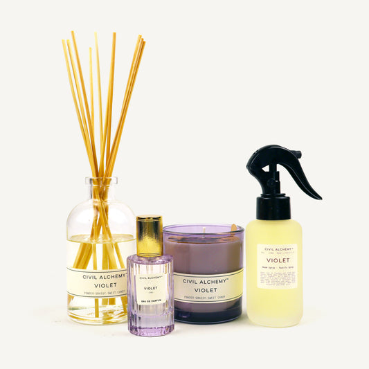 Collection of Civil Alchemy Violet fragrance products including diffuser, candle, and spray bottle on a white background.