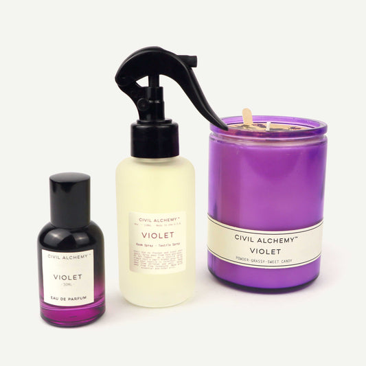 Three 'Civil Alchemy Violet' products including a spray bottle, a candle, and a perfume on a white background.