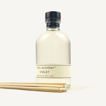 Bottle of Civil Alchemy Violet fragrance with reed diffuser sticks on a white background