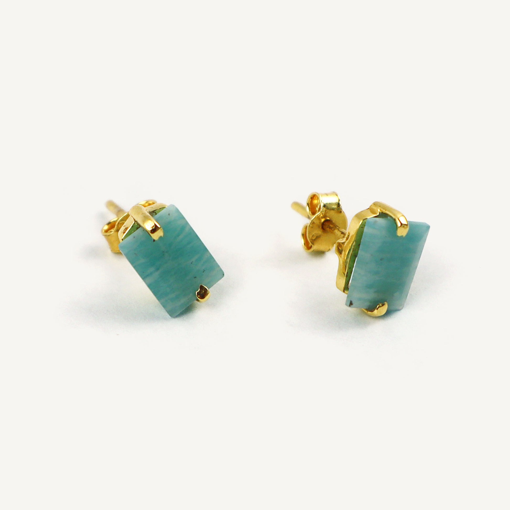 Pair of turquoise earrings with gold posts on a white background