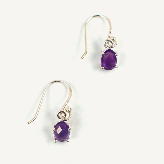 Pair of purple gemstone earrings on a white background