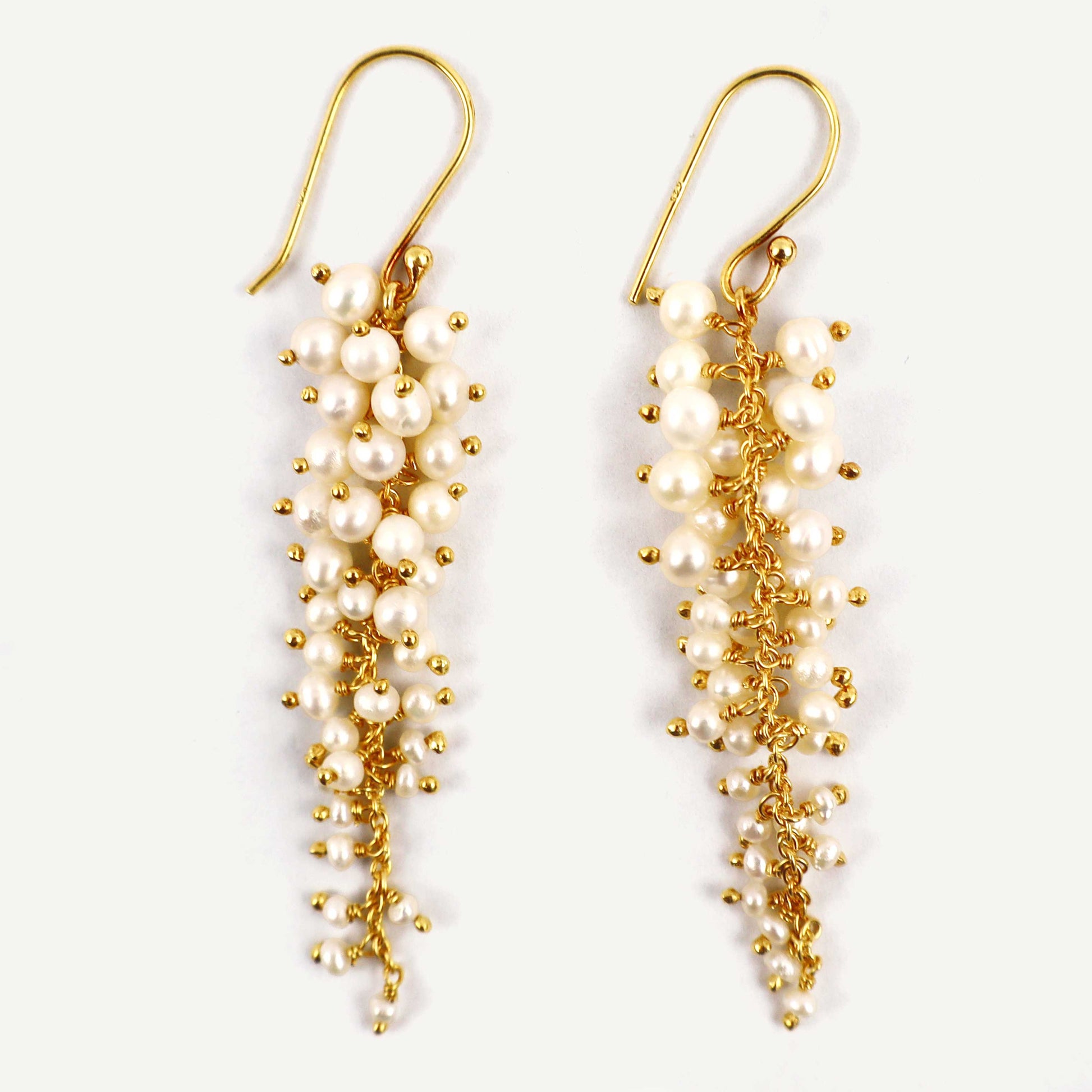 Pair of pearl and gold drop earrings on a white background