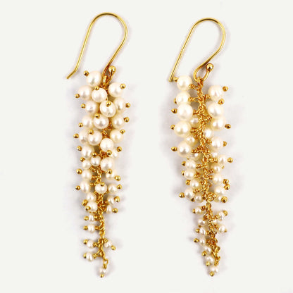 Pair of pearl and gold drop earrings on a white background
