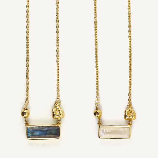 Two gold necklaces with gemstone pendants on a white background