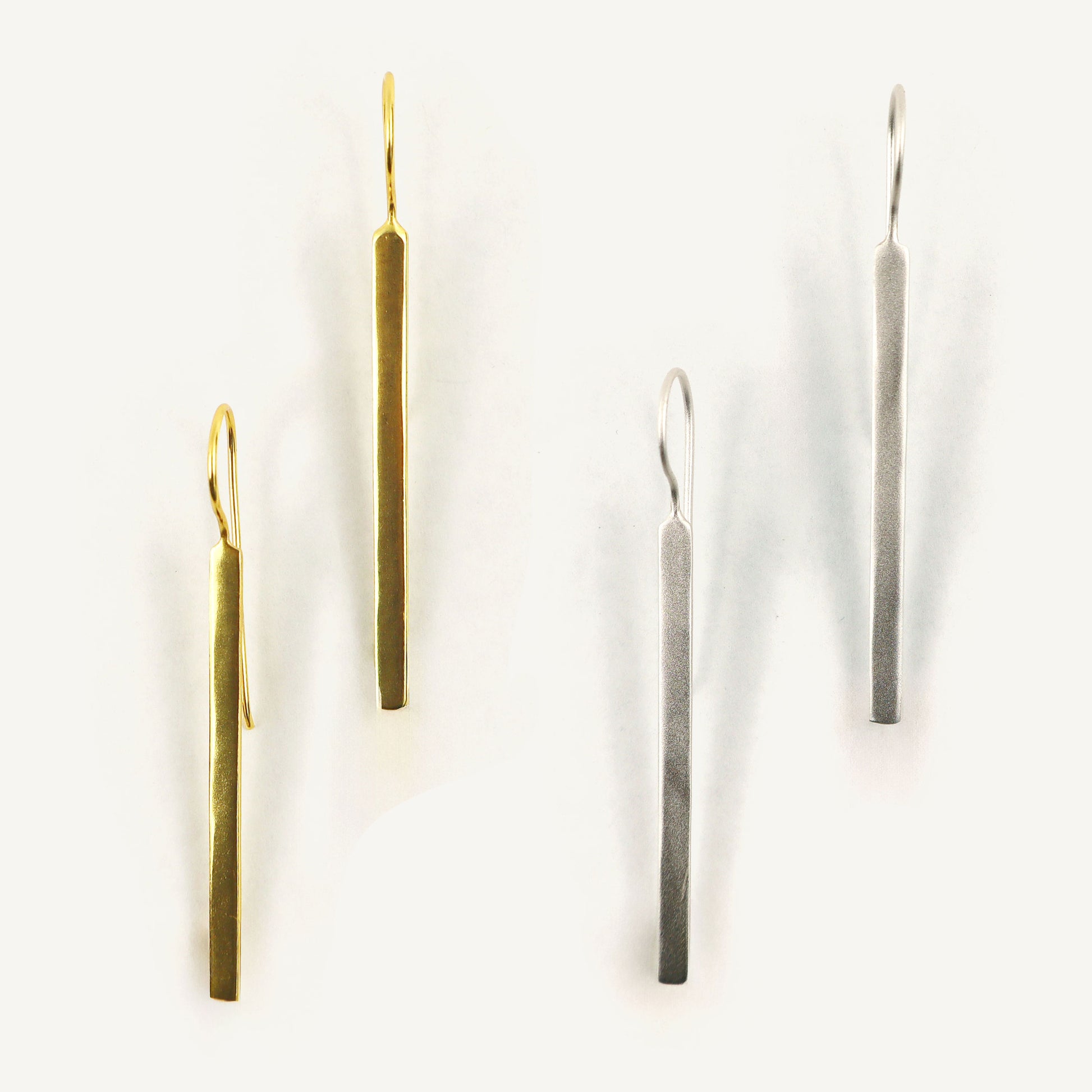 Two pairs of long, thin earrings on a white background