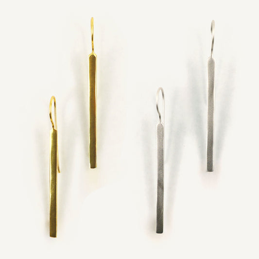 Two pairs of long, thin earrings on a white background