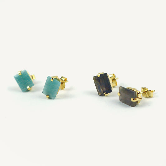 Gold-framed gemstone earrings on a white background