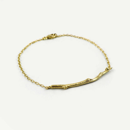 Gold bracelet with a branch-like design on a white background