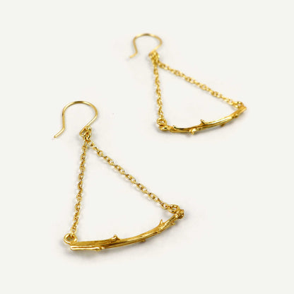 Gold branch-like earrings on a white background
