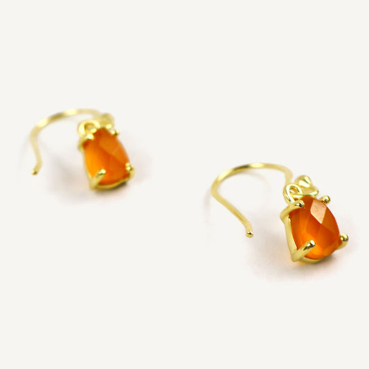 Gold earrings with orange gemstones on a white background