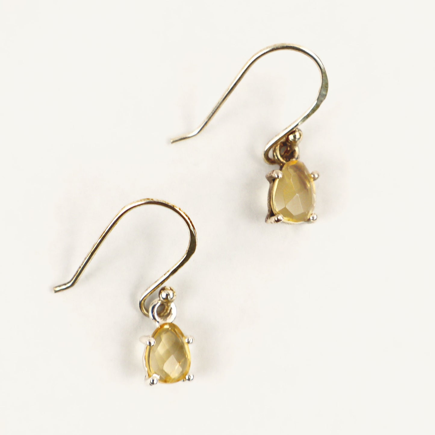 Silver earrings with yellow gemstones on a white background