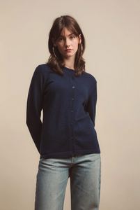 Woman wearing a navy cardigan and light blue jeans against a beige background