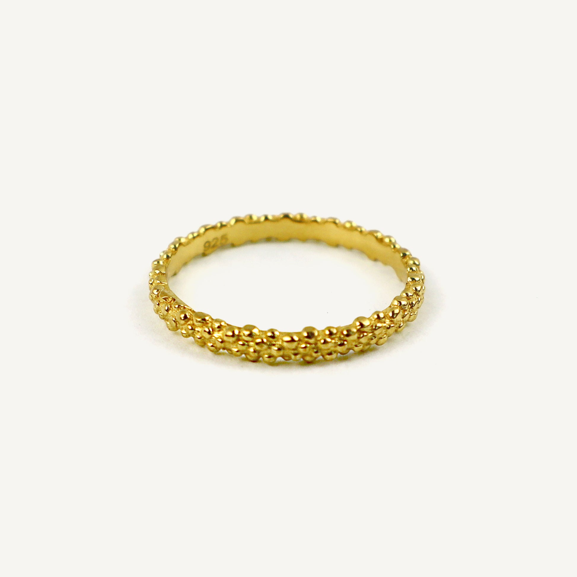 Gold ring with textured design on a white background