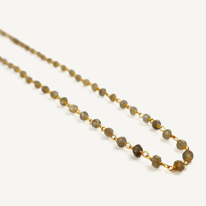Necklace with gray beads and gold chain on a white background