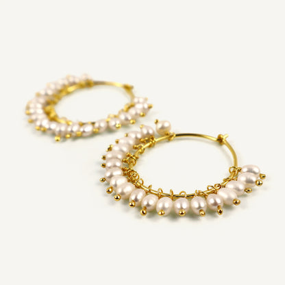 Gold hoop earrings with pearl accents on a white background