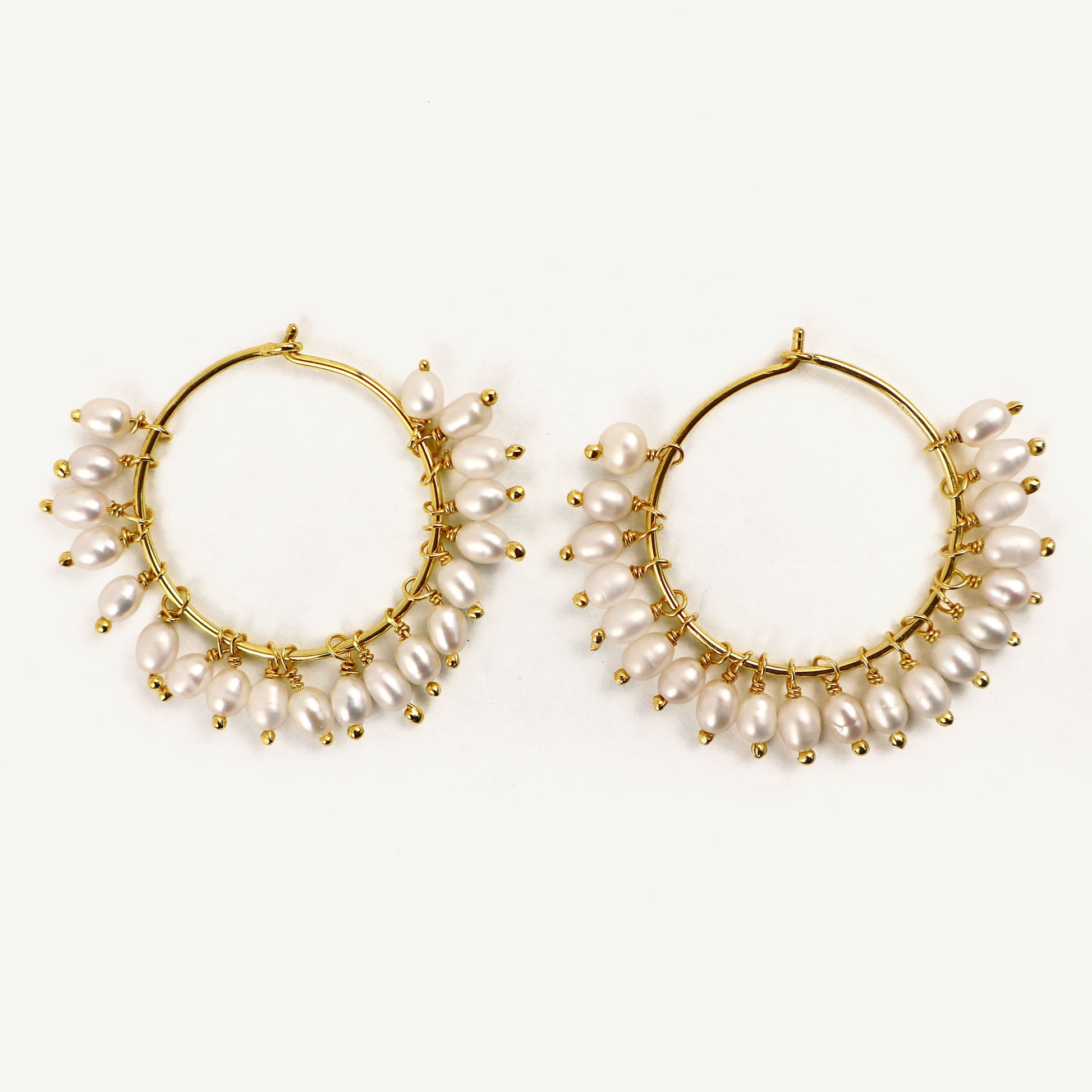 Gold hoop earrings with pearl accents on a white background