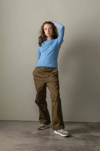 Person wearing a blue sweater and brown pants against a plain background