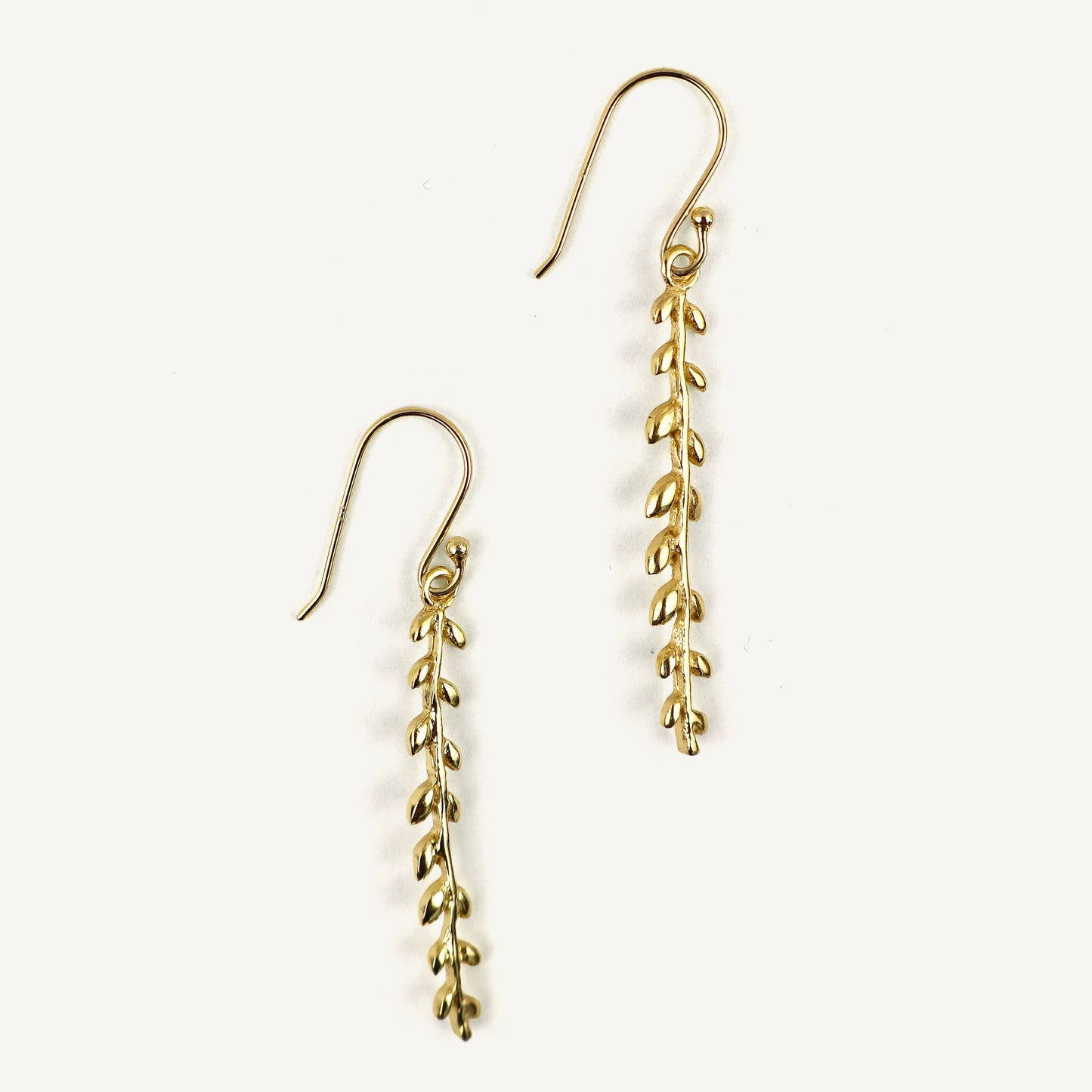 Gold leaf-shaped earrings on a white background