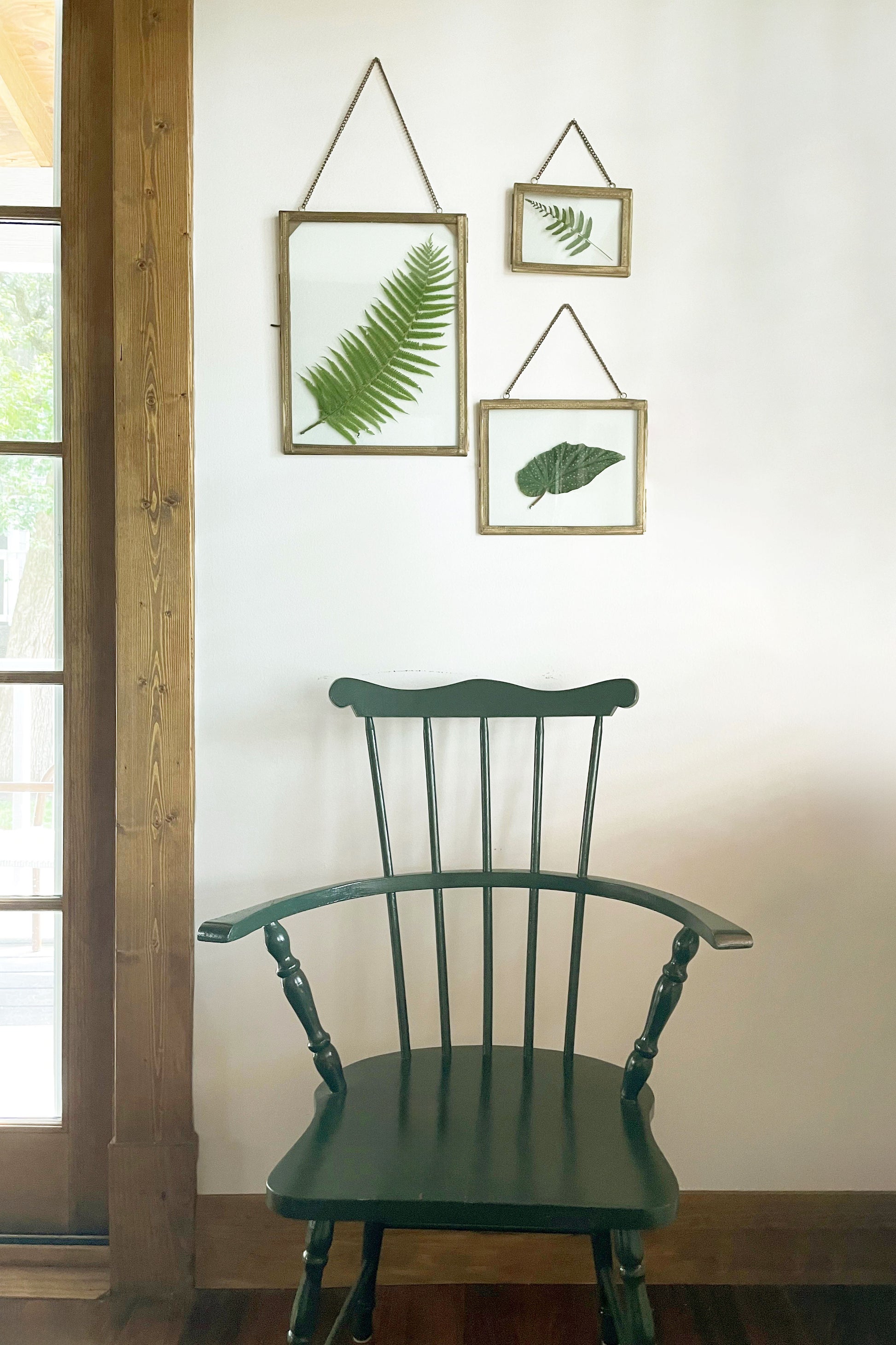 Green chair in front of a wall with framed leaf pictures