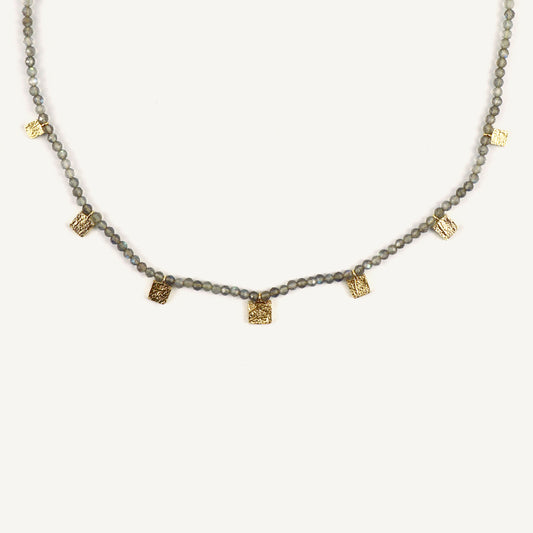 Necklace with alternating gray beads and gold pendants on a white background