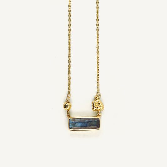 Gold necklace with a blue stone pendant on a white background