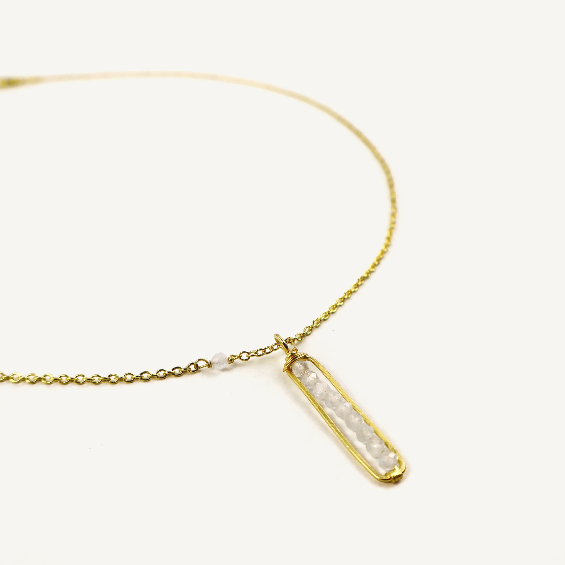 Gold necklace with a bar-shaped pendant on a white background