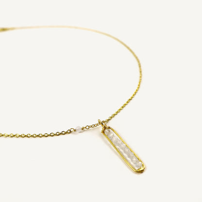 Gold necklace with a bar-shaped pendant on a white background