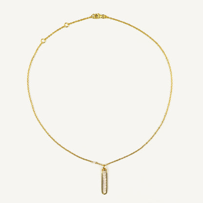 Gold necklace with a vertical pendant on a light beige background