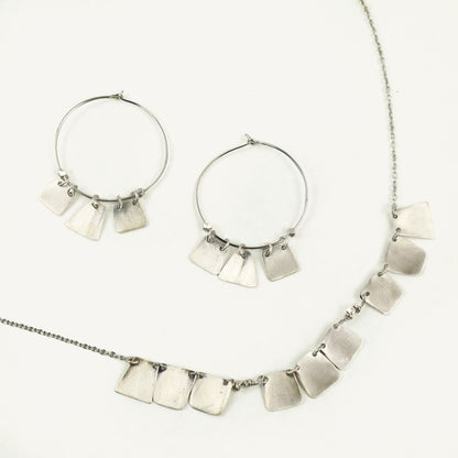 Silver necklace and hoop earrings on a white background