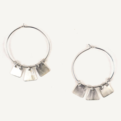 Silver hoop earrings with dangling tags on a white background