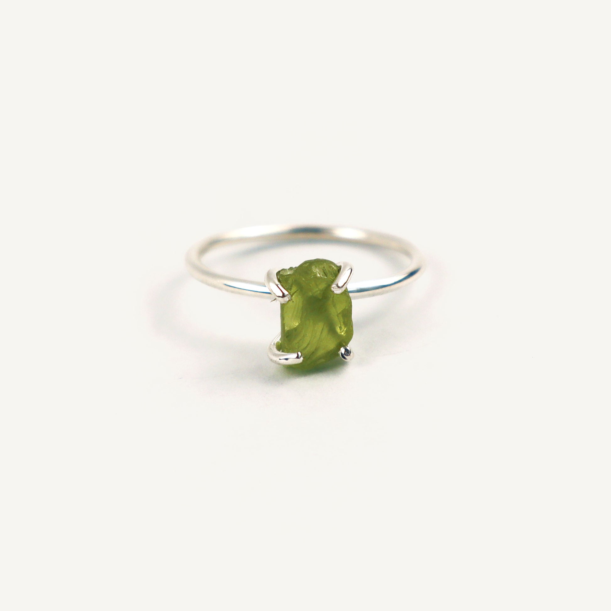 Silver ring with a green gemstone on a white background
