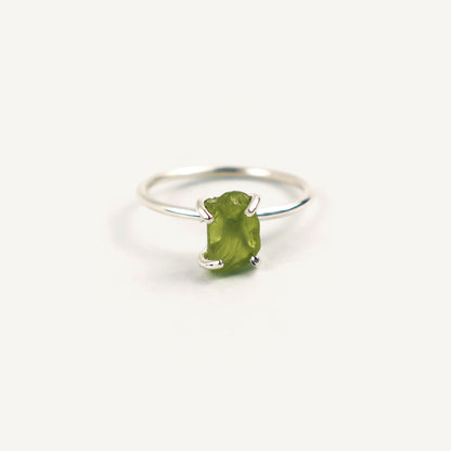 Silver ring with a green gemstone on a white background