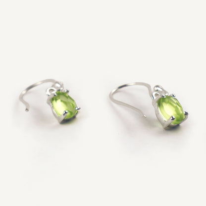 Pair of silver earrings with green gemstones on a white background