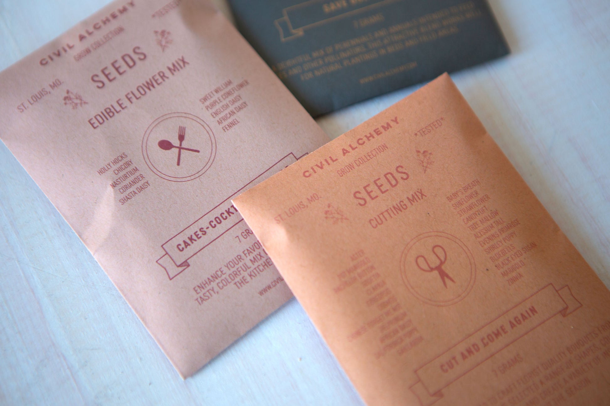 Two packets of Civil Alchemy Seeds on a light surface