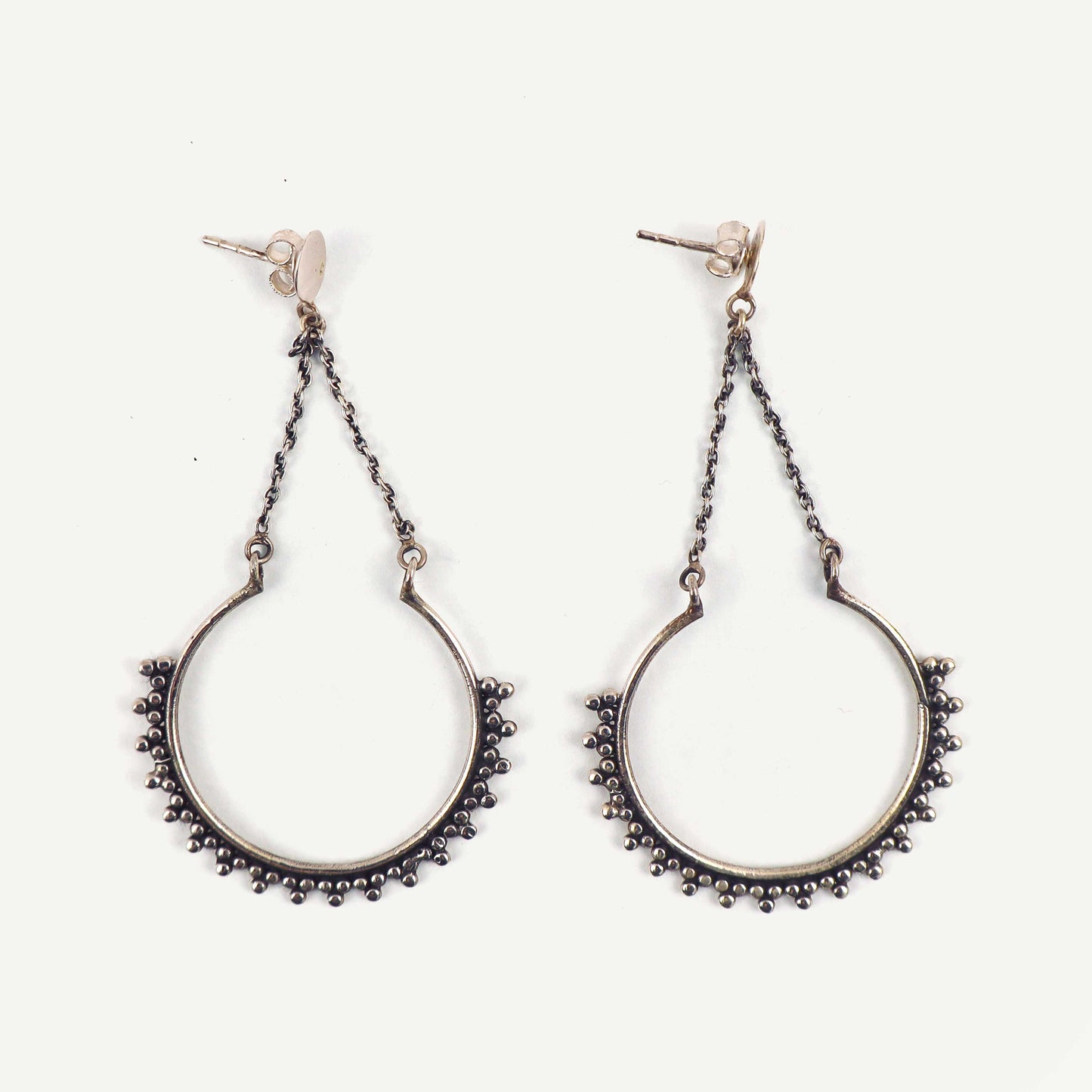 Pair of silver hoop earrings with chain details on a white background