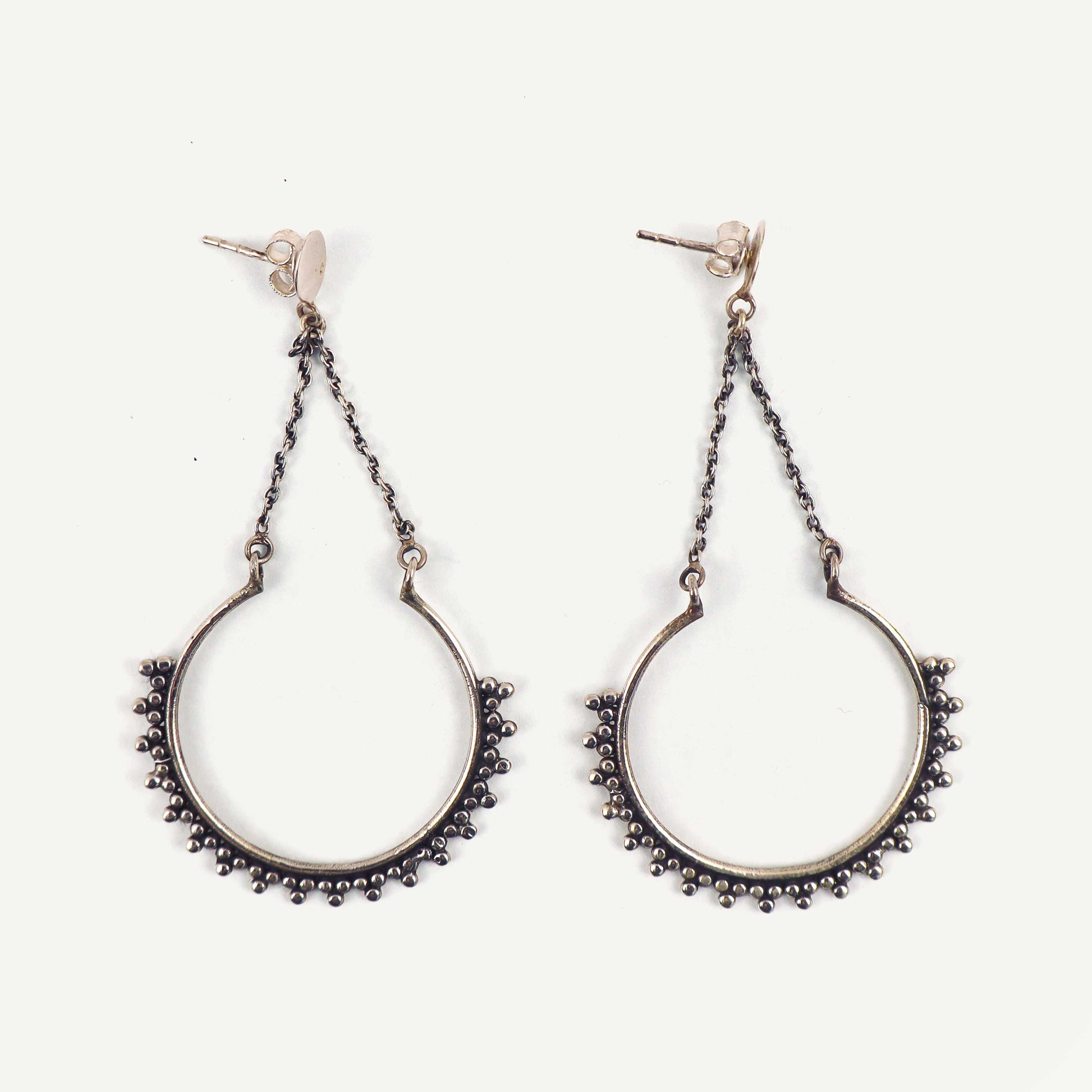 Pair of silver hoop earrings with chain details on a white background