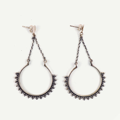 Pair of silver hoop earrings with chain details on a white background