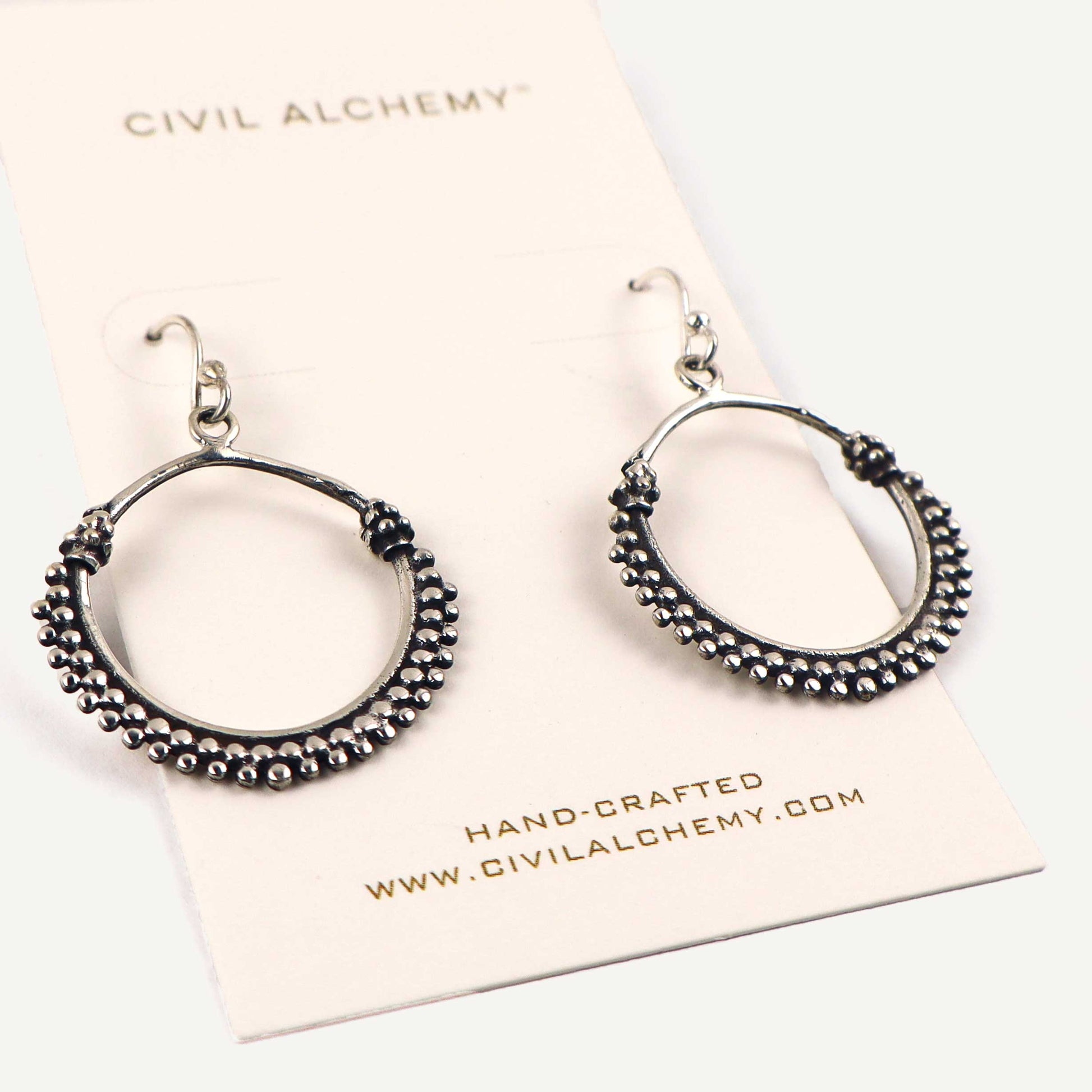 Pair of silver hoop earrings on a Civil Alchemy branded card.