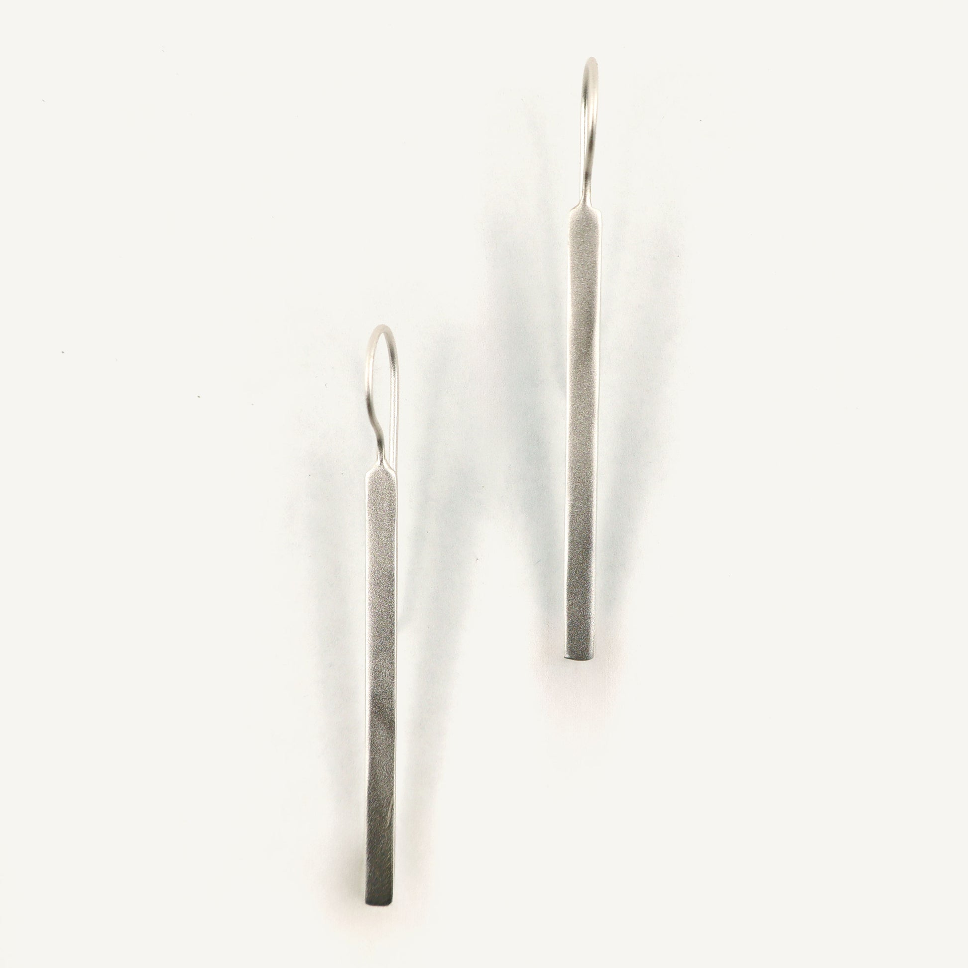 Pair of silver bar earrings on a white background