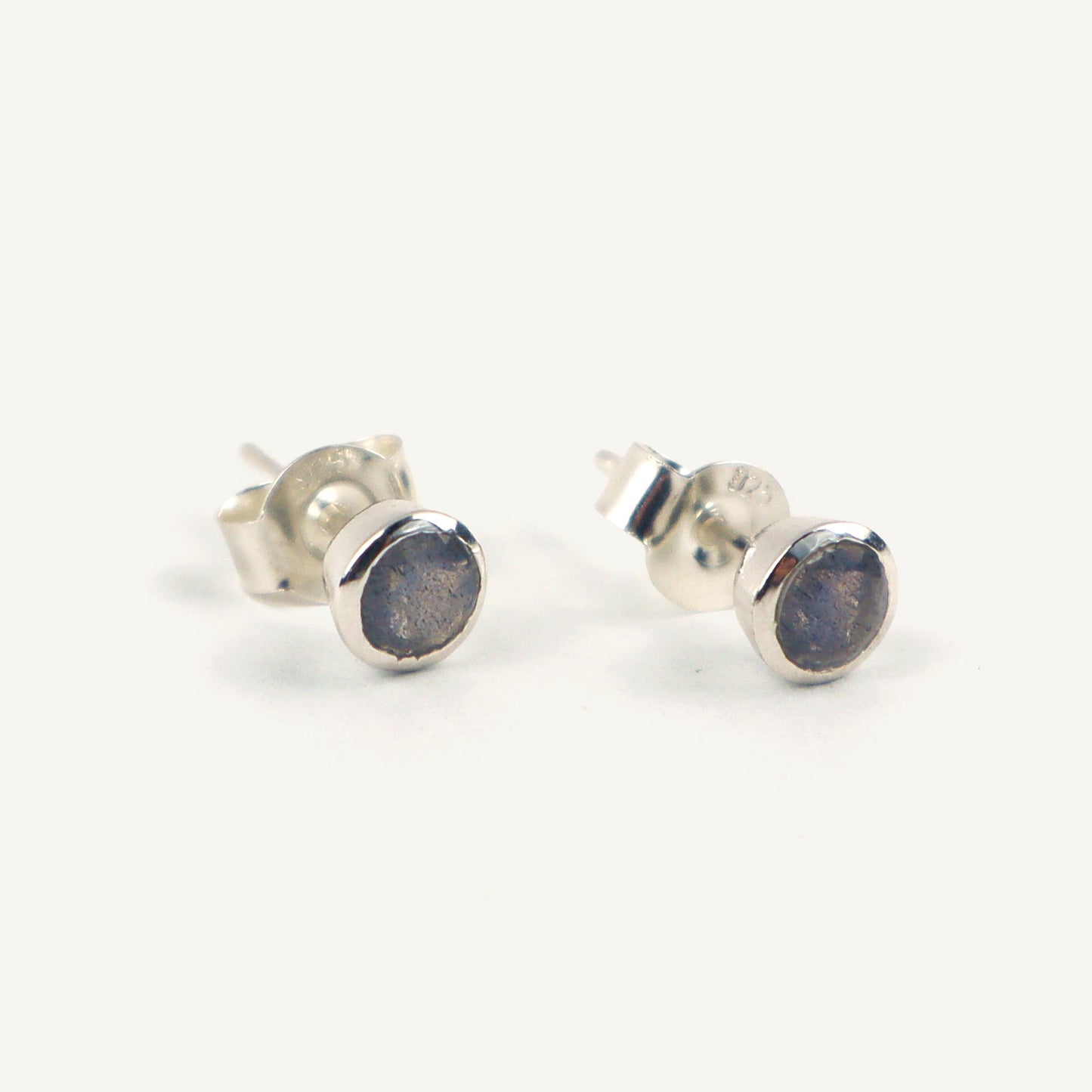 Silver stud earrings with a blue stone on a white background
