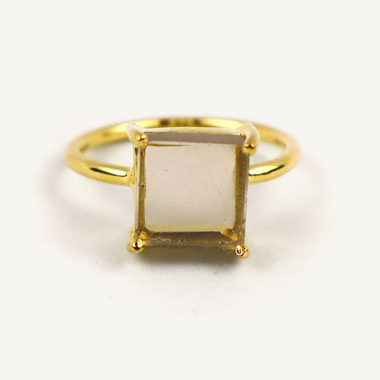 Gold ring with a square-cut gemstone on a white background