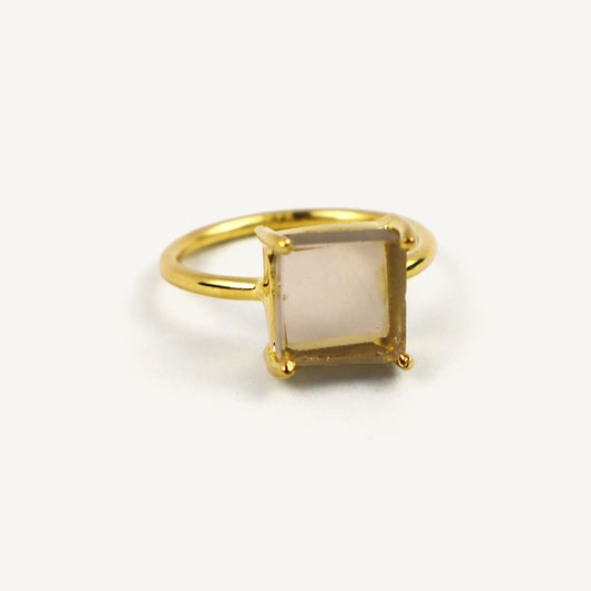 Gold ring with a square stone on a white background