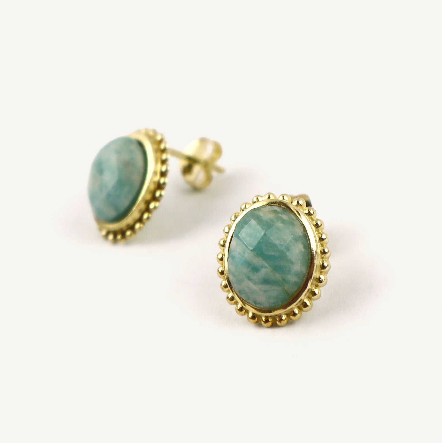 Gold-framed earrings with green gemstones on a white background