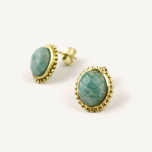 Gold-framed earrings with green gemstones on a white background