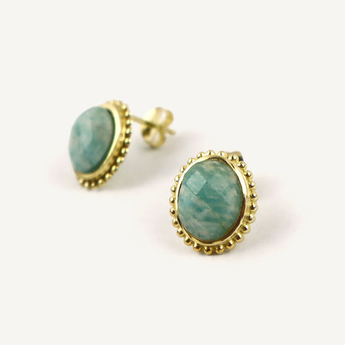 Gold-framed earrings with green gemstones on a white background