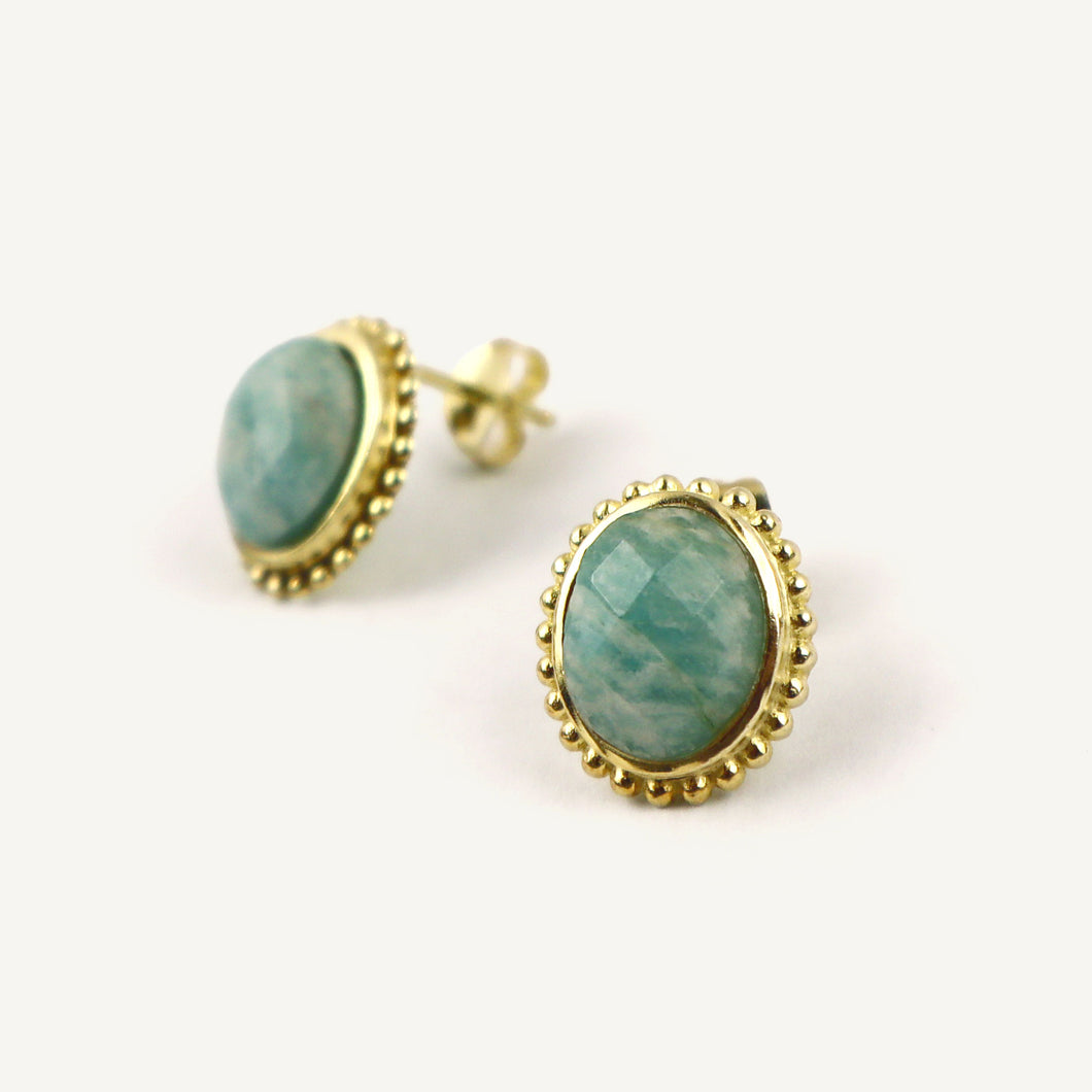 Gold-framed earrings with green gemstones on a white background
