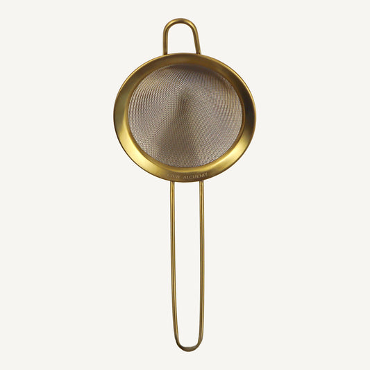 Gold-colored mesh strainer on a white background