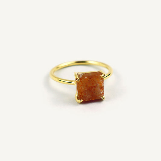 Gold ring with a red gemstone on a white background