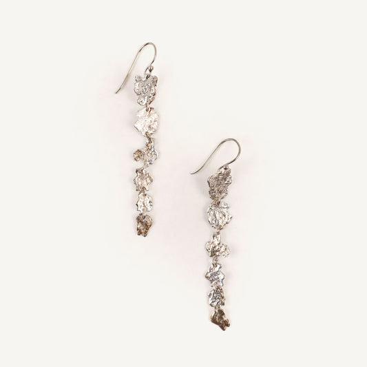 Pair of silver floral earrings on a light beige background